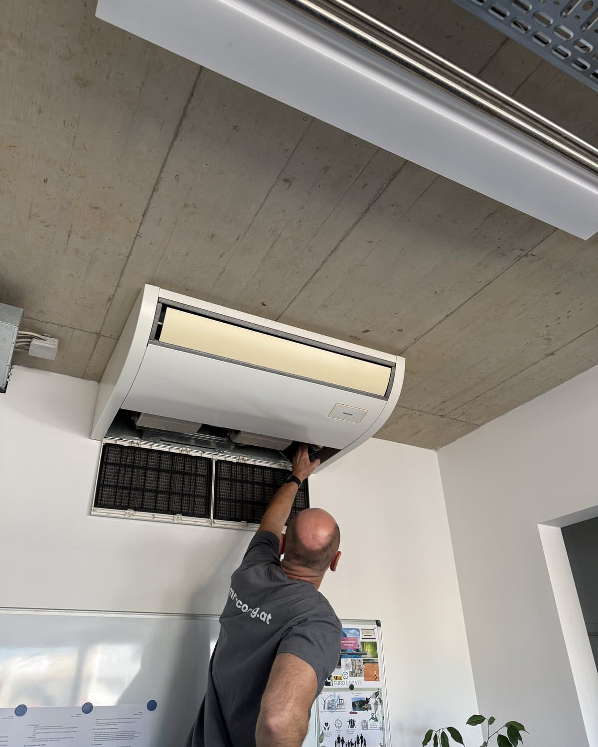 Monteur von MR Cooling beim Filterwechsel an einem Deckengerät im Büro